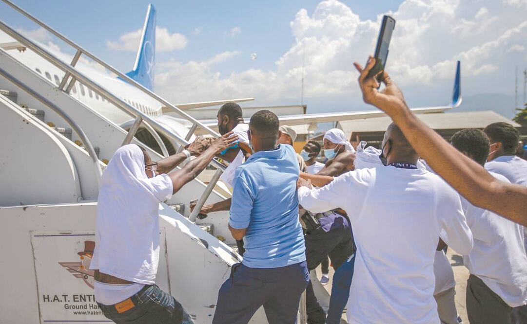 Haitianos deportados de Estados Unidos intentan abordar el mismo avión en el que fueron repatriados, en la pista del Aeropuerto Internacional Toussaint Louverture, en Puerto Príncipe. Foto: Joseph Odelyn. AP