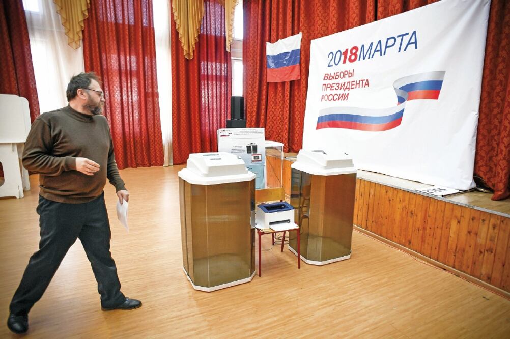 Miembros de la comisión de elección local preparaban ayer las máquinas de votación en una de las casillas instaladas para los comicios de hoy (ALEXANDER NEMENOV. AFP)