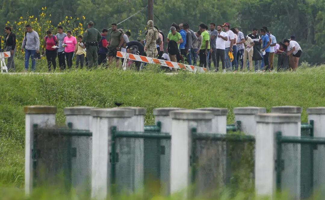 Migrantes hablan con funcionarios junto a una carretera cerca de Río Grande tras cruzar la frontera entre Texas y México. Foto. AP