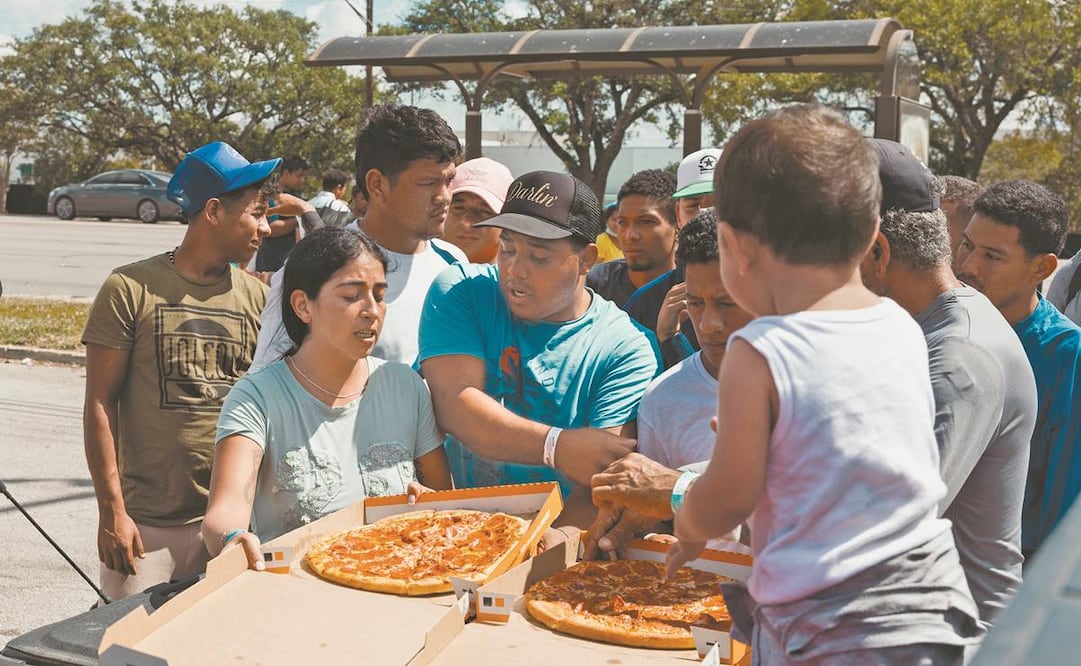 Una lugareña distribuye pizzas a migrantes venezolanos en San Antonio, Texas. Foto: AFP.