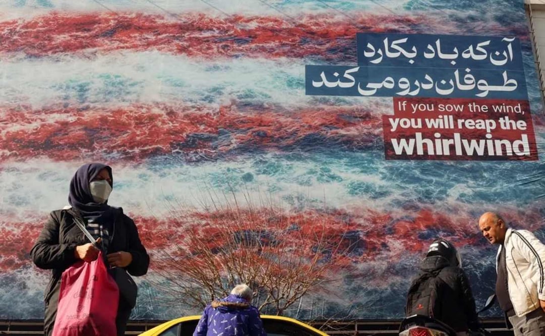 Iraníes caminan cerca de un enorme cartel antiestadounidense colgado en la plaza Enqelab de Teherán. Foto: EFE