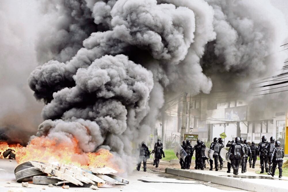 Policías pasan junto a una barricada montada por los huelguistas, en Bogotá (FERNANDO VERGARA. AP)