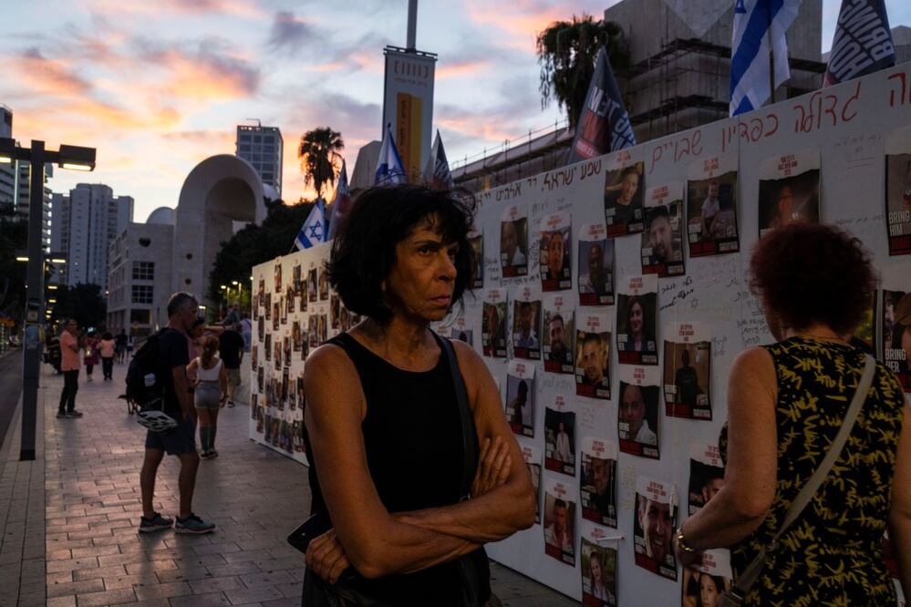 La gente revisa fotos de israelíes que están en manos de Hamas, en Gaza. Las imágenes fueron desplegadas en un muro en Tel Aviv. PETROS GIANNAKOURIS. AP