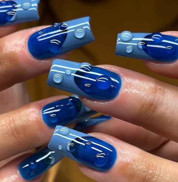 Uñas francesas bicolor azul con gotas combina con el concepto de agua. Foto: Instagram @groovynailsbybea