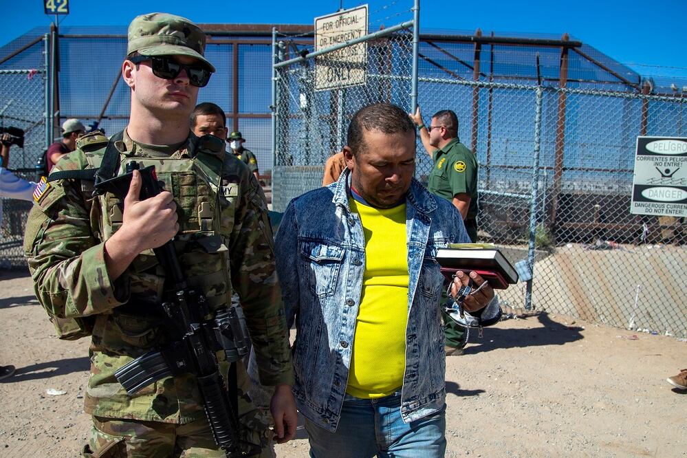 Migrantes son escoltados por un soldado del ejército estadounidense tras entrar en El Paso, Texas, procedentes de Ciudad Juárez, México, para ser procesados por las autoridades de inmigración, el 10 de mayo de 2023. AP