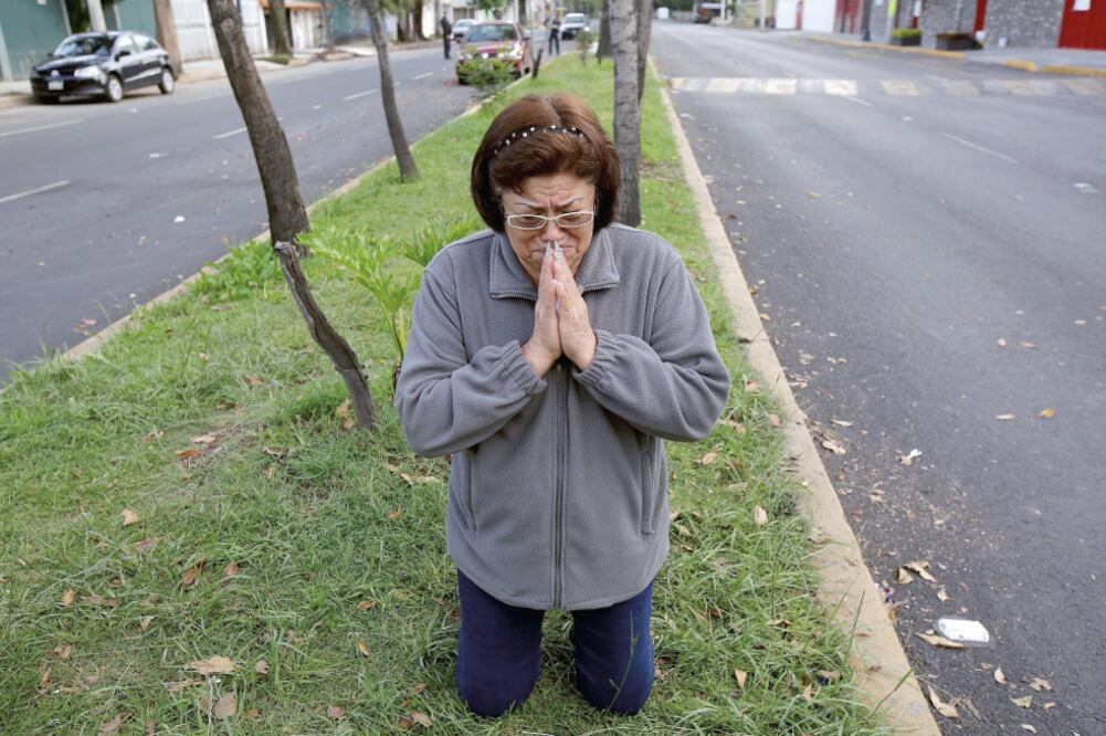 Una mujer llorando se hincó a rezar después del sismo que se sintió ayer en la mañana en la Ciudad de México. (JOSÉ LUIS GONZÁLEZ. REUTERS)