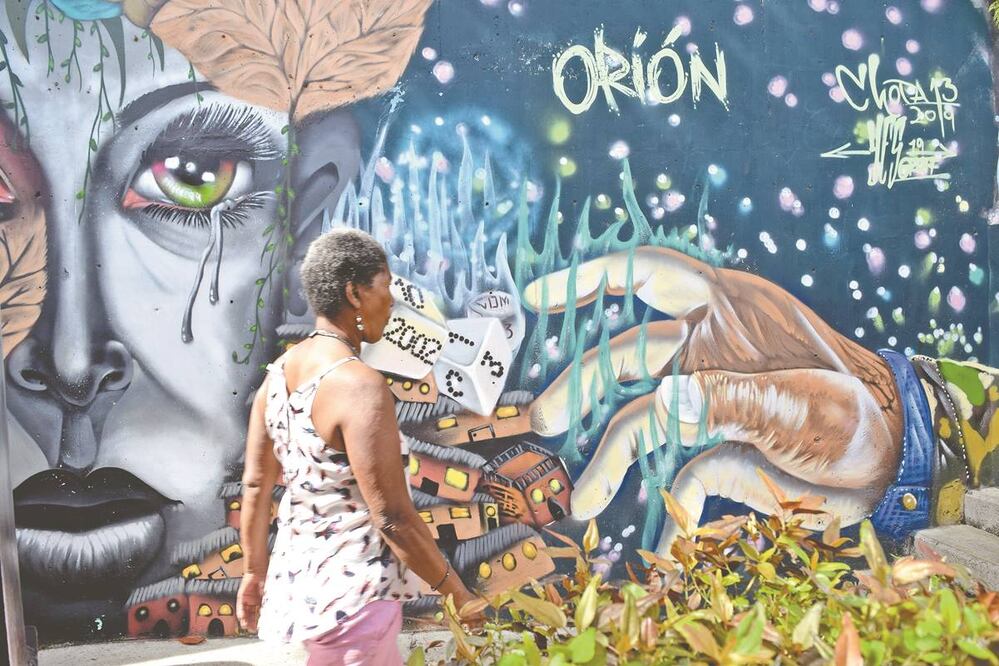 Una de las principales pinturas registra la tragedia en el operativo Orión; se observa una mano que avienta unos dados con los números y letras 10, 16, 2002, C 13, y que caen sobre casitas que sucumben a su fuerza. FOTOS: SONIA SIERRA. EL UNIVERSAL