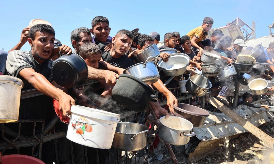 Hombres y niños palestinos extienden sus ollas vacías para recibir arroz cocido de un comedor social en la ciudad de Gaza, en agosto de 2025. Naciones Unidas declaró oficialmente la hambruna en Gaza el 22 de agosto. Foto: AFP