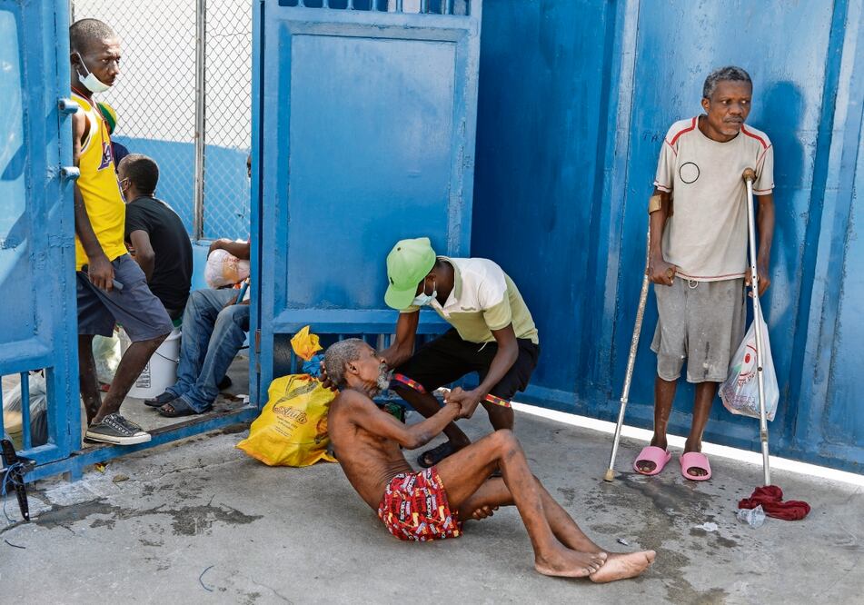 Un preso ayuda a otro en la Penitenciaría Nacional, tras la irrupción de bandas armadas que permitió la fuga de miles, en Puerto Príncipe. Foto: AP
