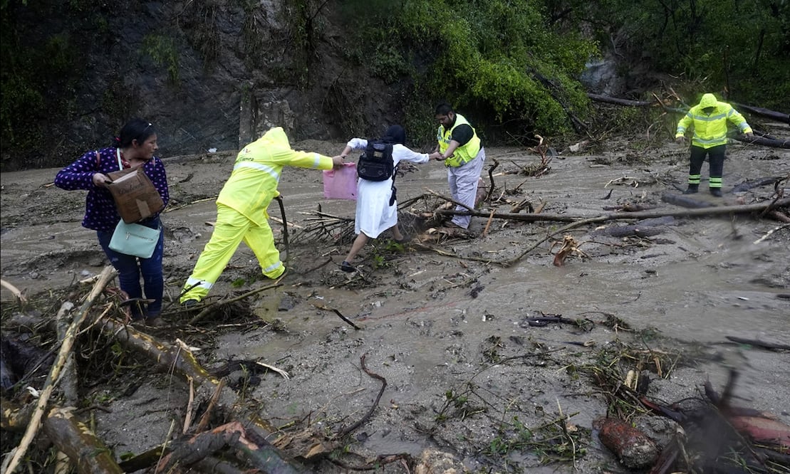 Gente recibe ayuda para cruzar una carretera bloqueada por un deslizamiento de tierra provocado por el huracán Otis cerca de Acapulco, Guerrero. Foto: AP