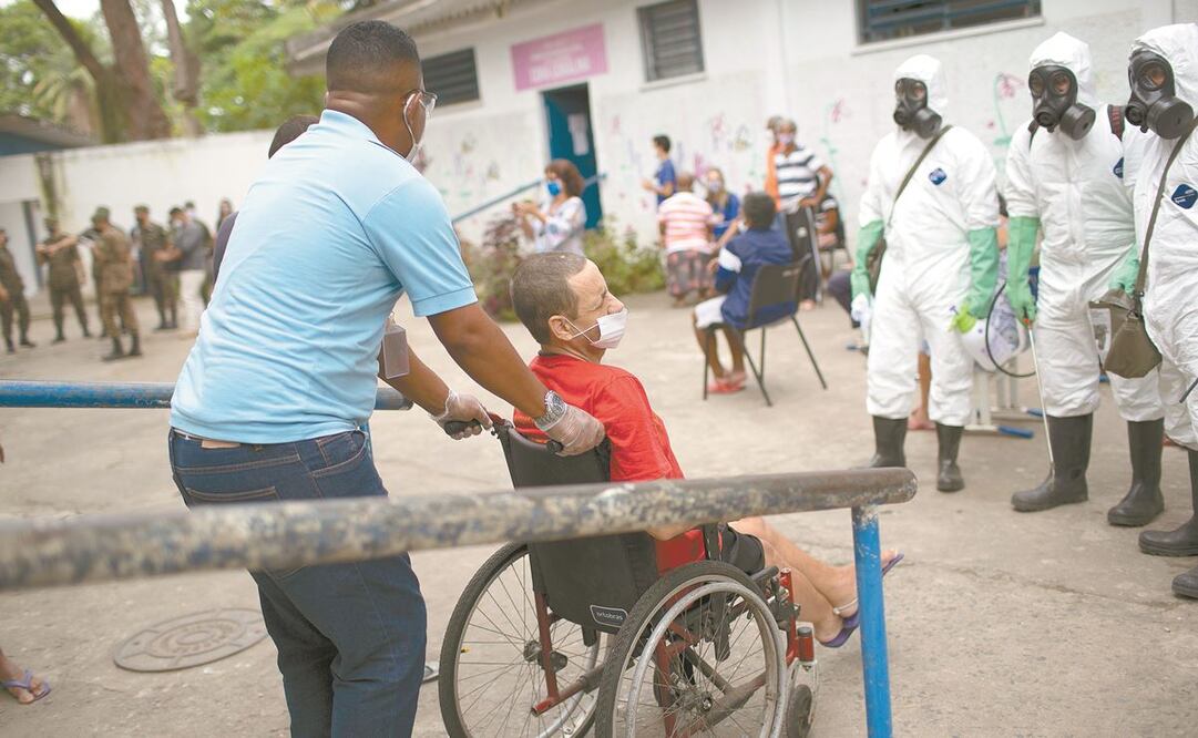 Un trabajador ayuda a una persona en silla de ruedas en Río de Janeiro. Para los expertos, la discapacidad ha sido invisibilizada en la pandemia. Foto: SILVIA IZQUIERDO. AP