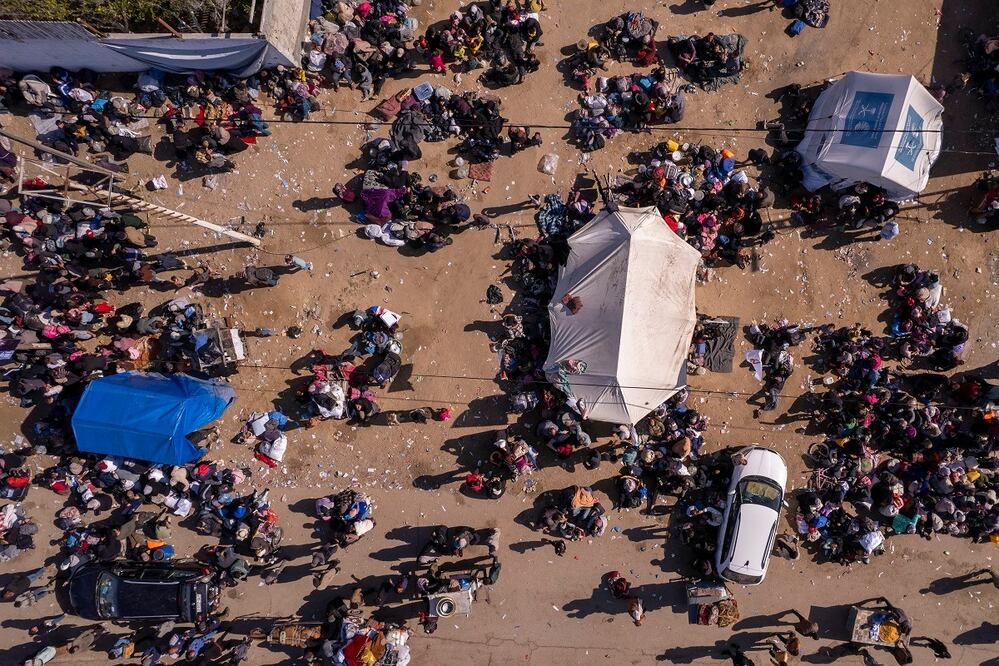 Una fotografía aérea tomada por un dron muestra a palestinos desplazados reunidos con sus pertenencias cerca de un control de carretera en la calle al Rashid, mientras esperan para regresar a sus hogares en el norte de la Franja de Gaza. FOTO: MOHAMMAD ABU SAMRA. AP