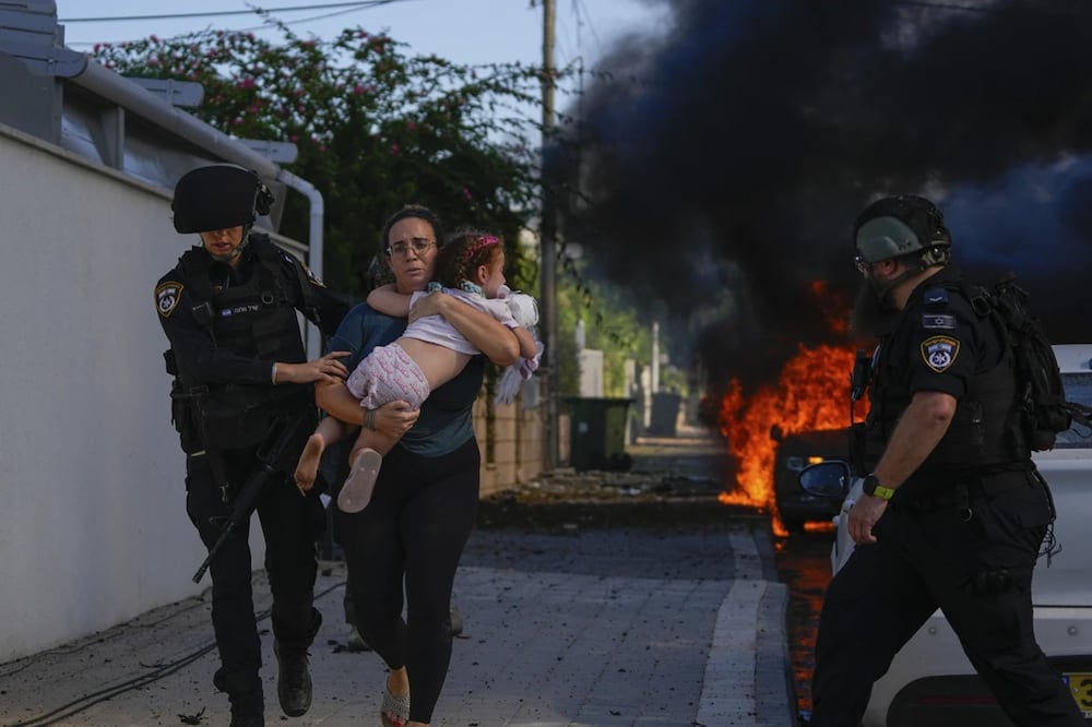 Agentes de policía evacuan a una mujer y un niño de un lugar alcanzado por un cohete lanzado desde la Franja de Gaza, en Ashkelon, al sur de Israel. Foto: AP