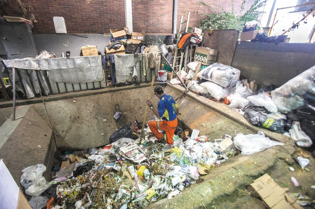 Los ayudantes de limpieza del mercado Sonora, con el apoyo de herramientas, empujan los desechos hacia abajo para que caigan al fondo en un contenedor, el cual es recogido por un camión de basura por la noche (YADÍN XOLALPA. EL UNIVERSAL)
