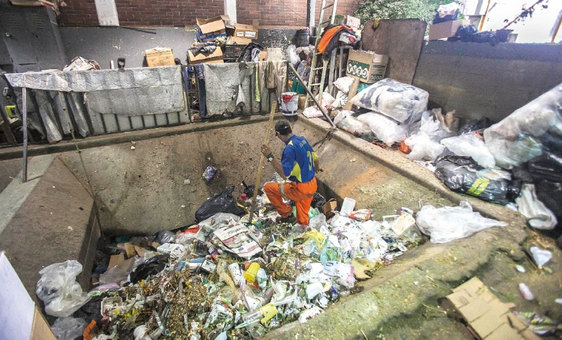 Los ayudantes de limpieza del mercado Sonora, con el apoyo de herramientas, empujan los desechos hacia abajo para que caigan al fondo en un contenedor, el cual es recogido por un camión de basura por la noche (YADÍN XOLALPA. EL UNIVERSAL)