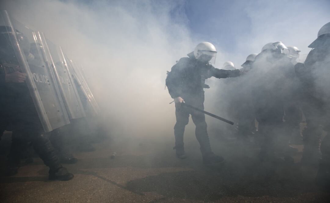 Police officers in riot gear joined by KFOR troops use tear gas to disperse an angry crowd of mock protesters during a riot control exercise – Photo: Visar Kryeziu/AP