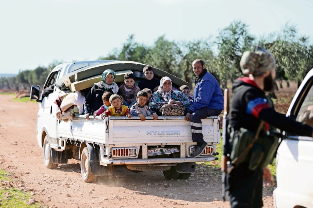 Desplazados sirios viajaron ayer en la parte trasera de un camión para huir de la guerra que vive el país desde hace siete años, en la ciudad de Inab ()