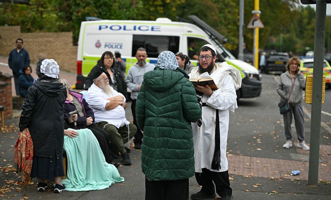 Integrantes de la comunidad judía local se encuentran en la calle frente a la sinagoga de la Congregación Hebrea de Heaton Park en Crumpsall, al norte de Manchester, el 2 de octubre de 2025, tras un ataque en la sinagoga. Foto: AFP