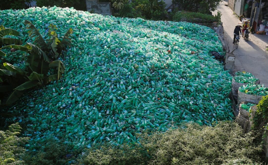 Vietnamese women drive past recyclable plastic bottles at Xa Cau village, outside Hanoi, Vietnam - Photo: Kham/REUTERS