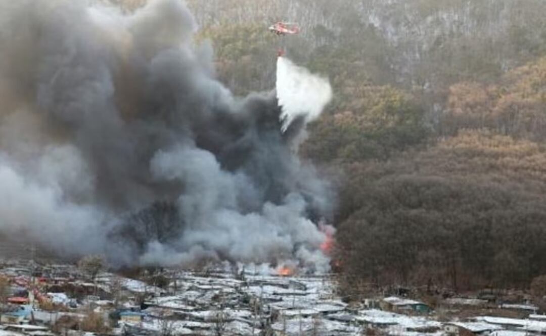 Un helicóptero de los bomberos sobrevuela el incendio en el suburbio de Guryong, en las afueras de Seúl. Foto: AFP