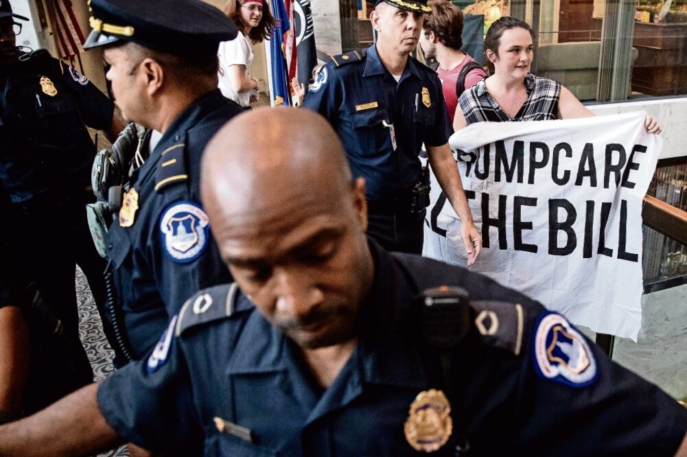 Policías del Capitolio se preparaban para arrestar a un grupo que protestó ayer contra Trumpcare a las afueras de las oficinas del senador Dean Heller (ANDREW HARNIK. AP)
