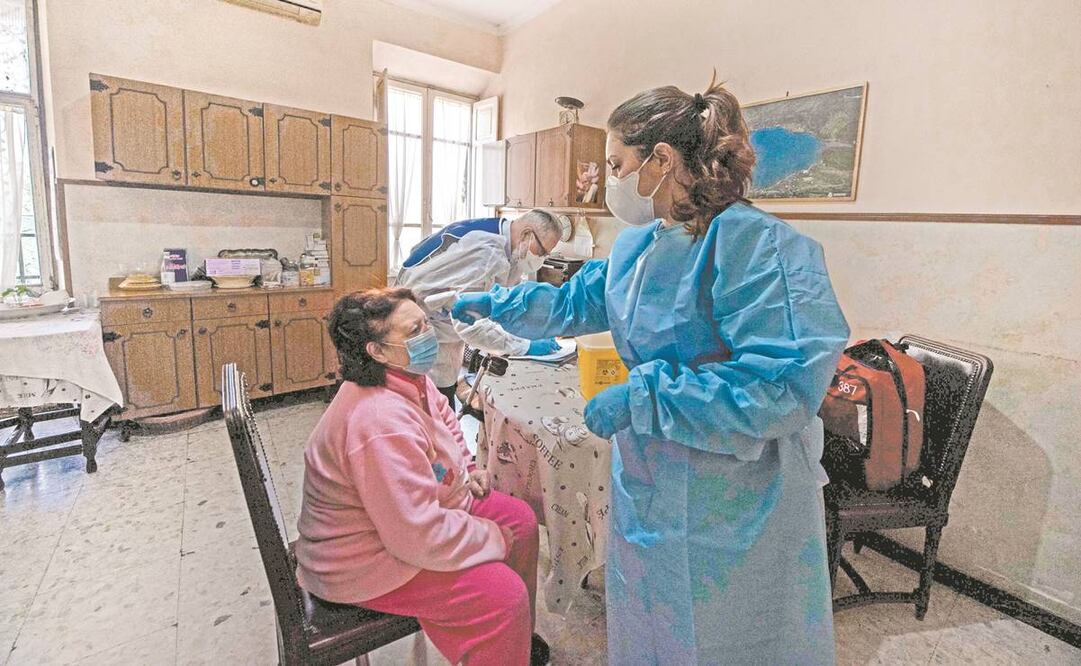 Una enfermera revisa la temperatura de una mujer, como parte del proceso para aplicarle la vacuna de Pfizer-BioNTech, en Roma. Foto: Tiziana Fabi/ AFP.