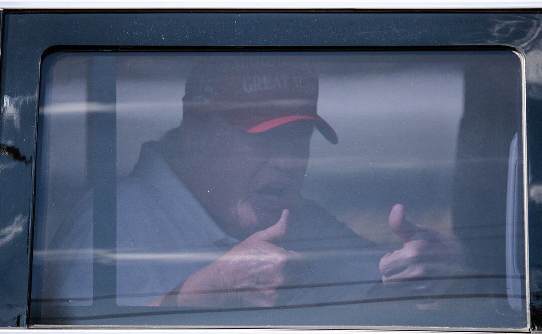 Donald Trump, se sienta en la parte trasera de su limusina cuando sale del Trump International Golf Club en West Palm Beach, Florida. Foto: AFP