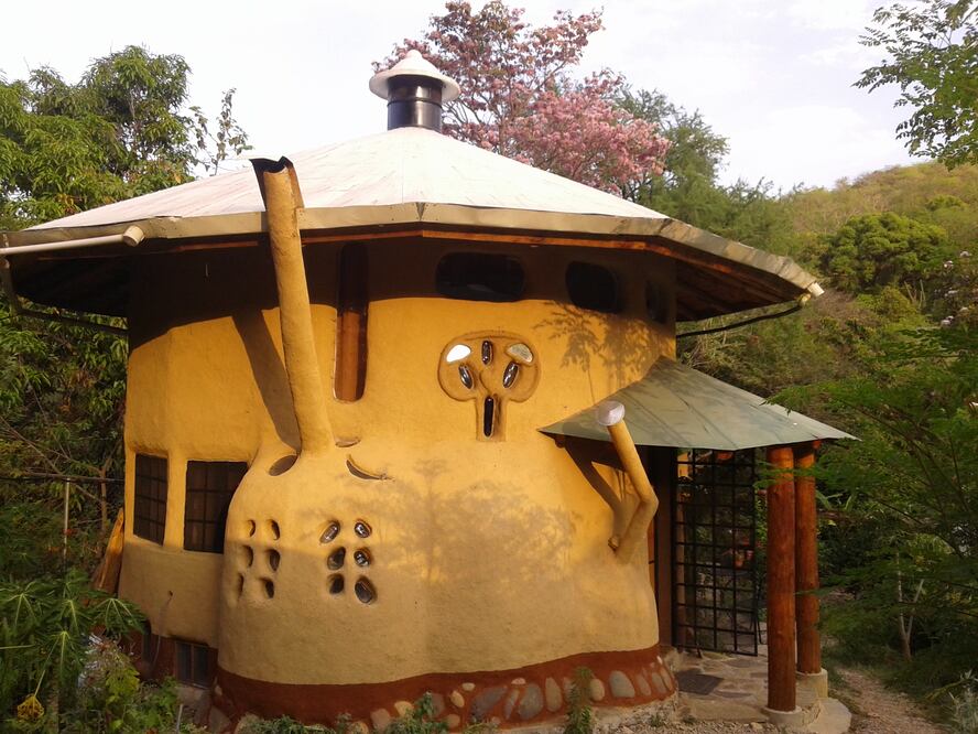 Casita Ecológica. Cabañas hechas de barro, rodeadas de árboles tropicales.