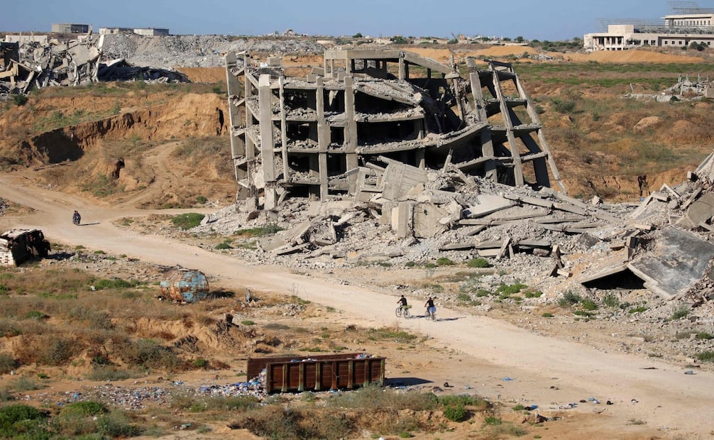 Palestinos circulan en bicicleta entre los restos de edificios destruidos por ataques en Ciudad de Gaza, mientras continúan las labores entre los escombros (20/06/2026). Foto: AFP