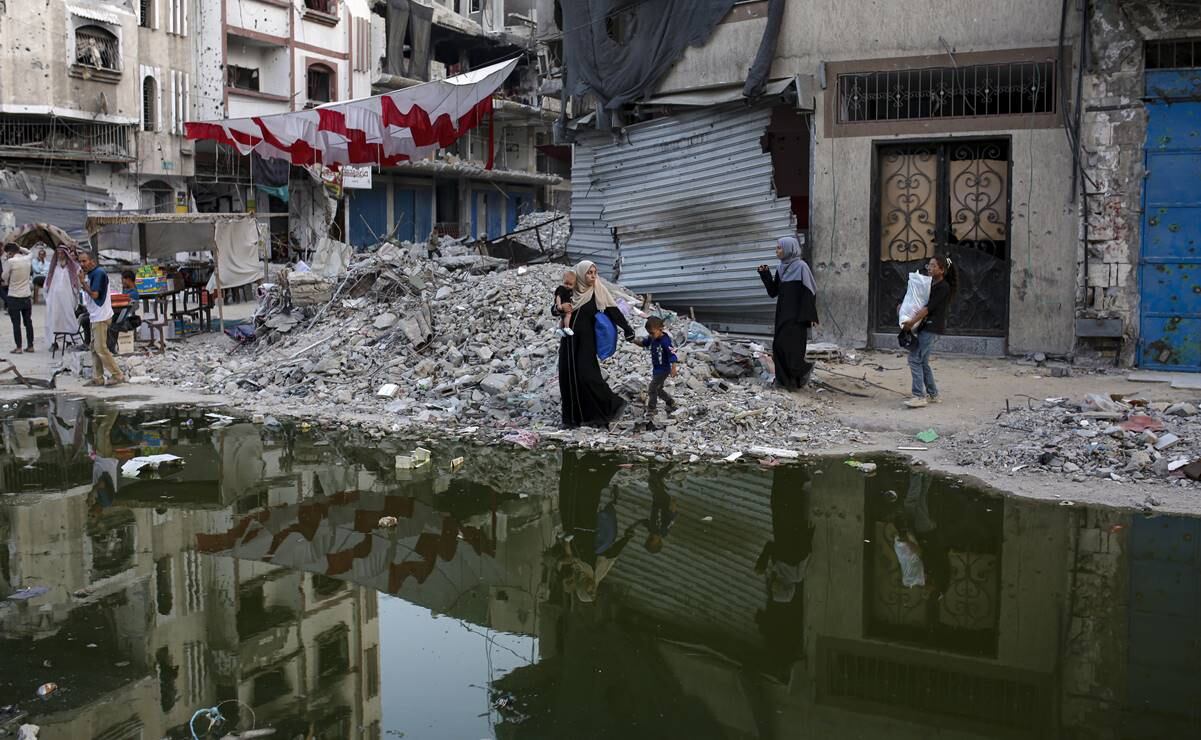 Palestinos caminan junto a una oscura franja de aguas residuales que fluyen hacia las calles de la ciudad sureña de Khan Younis. Foto: AP