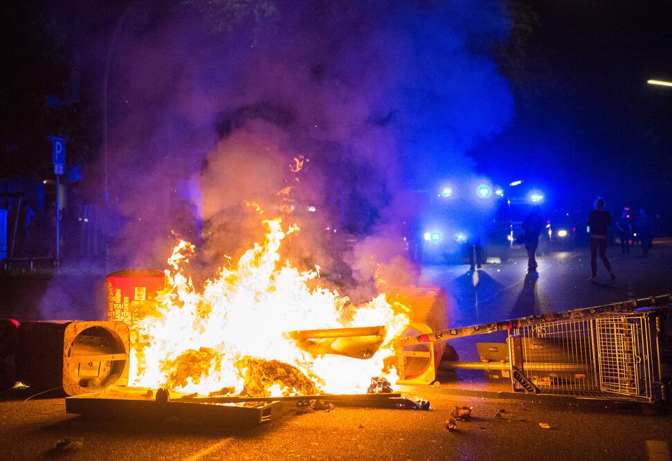Policías tras una barricada en llamas en la llamda zona de "Schanzenviertel", durante la cumbre del G20 en Hamburgo, en la madrugada. (AP)
