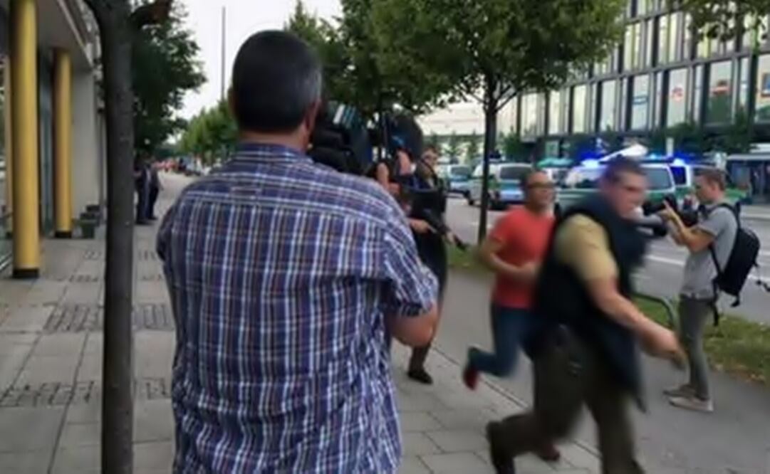 Armed police move past onlooking media responding to a shooting at a shopping center in Munich, Germany. (Photo: AP)