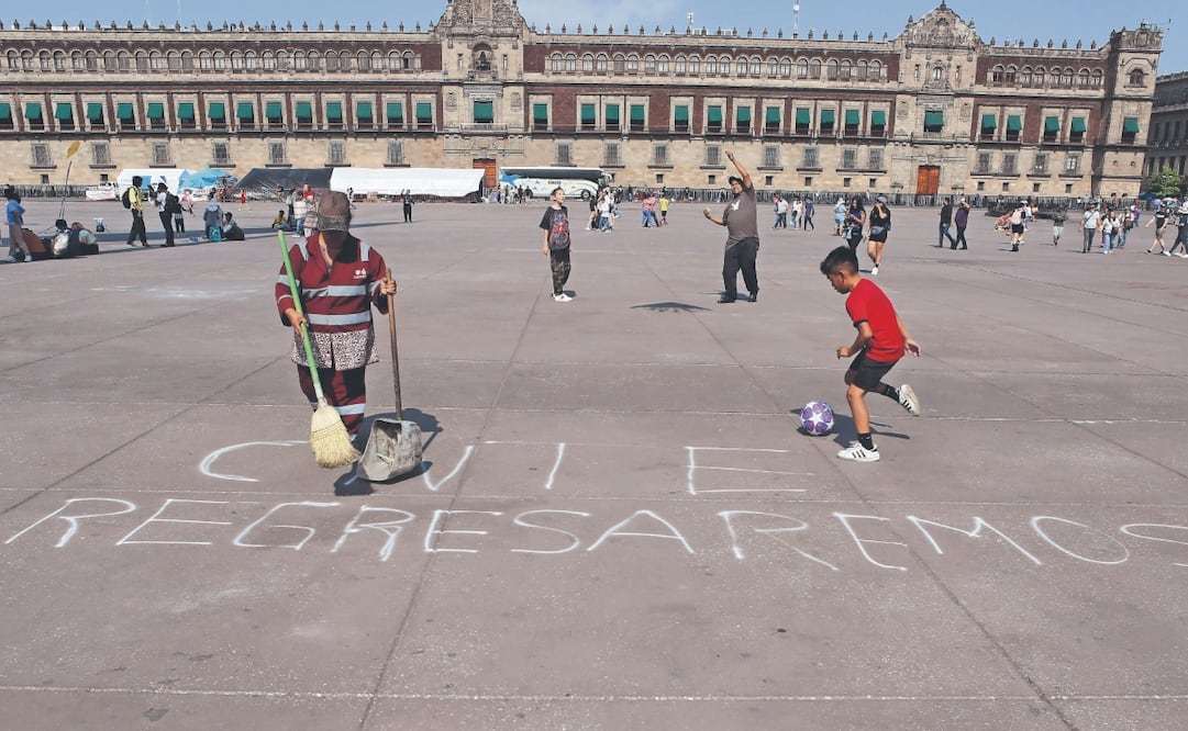 Personal de limpia retira restos de basura en la plancha del Zócalo capitalino, tras la salida del plantón de maestros de la CNTE, mientras que Jorge juega con su balón. Foto: Darío Luna/ EL UNIVERSAL