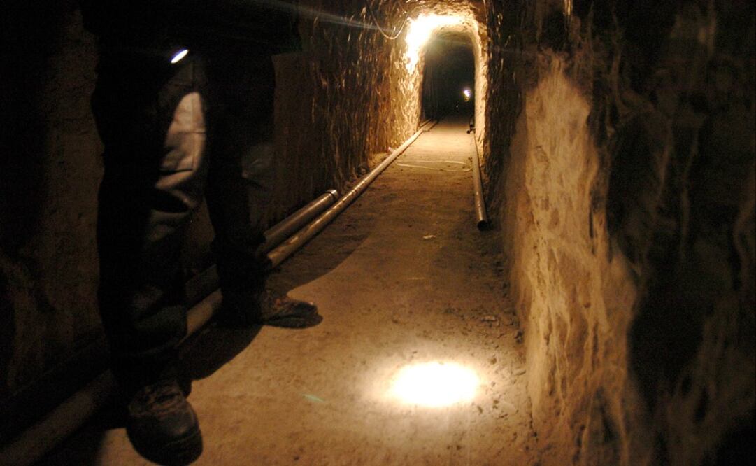 A Mexican federal police officer shines his flashlight on the ground of a sophisticated clandestine tunnel that passes under the US-Mexico border on Wednesday, Jan. 25, 2006 in Tijuana - Photo: David Maung/AP