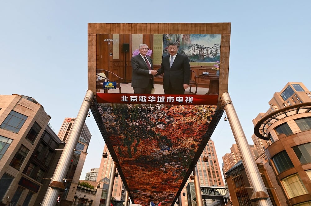 El cofundador de Microsoft, Bill Gates (izq.), con el presidente chino Xi Jinping, en una pantalla gigante afuera de un centro comercial en Beijing el 16 de junio de 2023. Foto: AFP
