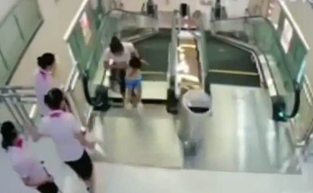 En décimas de segundo la mujer, más atenta a la vida de su hijo que a la suya, empuja a éste para que se aleje del agujero, mientras ella se hunde poco a poco, empujada por los escalones móviles Foto: Tomada de YouTube