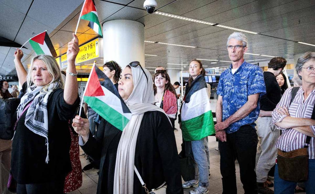 La gente ondea banderas palestinas mientras los participantes de la «Marcha Global a Gaza» parten del aeropuerto de Schiphol con destino a Egipto. Foto: EFE/EPA/Ramon van Flymen