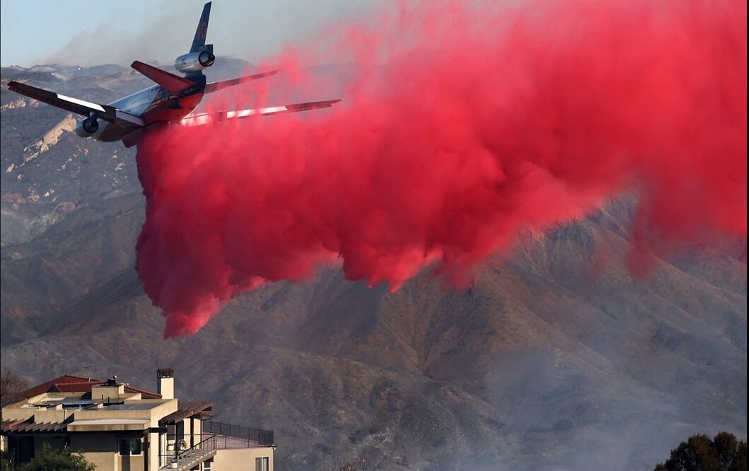 Un avión de extinción de incendios arroja el retardante de fuego Phos-Chek mientras el incendio continúa en Pacific Palisades, California, el 7 de enero de 2025. Foto: AFP
