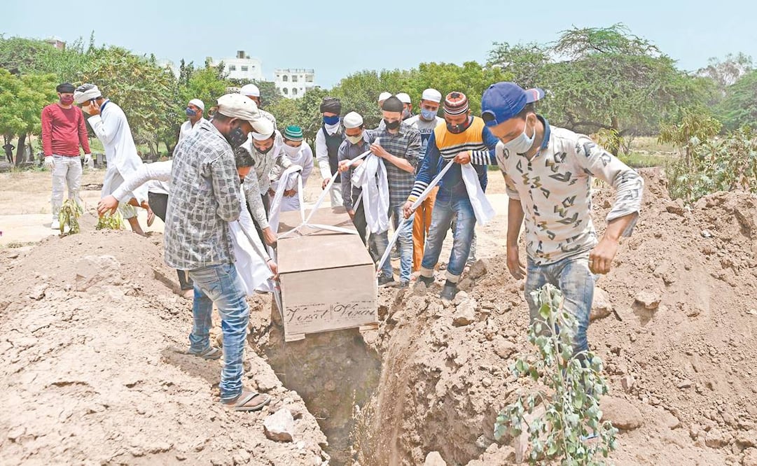 Trabajadores del cementerio, familiares y amigos se preparan para enterrar el cuerpo de una víctima del coronavirus, en Nueva Delhi. Foto: Sajjad Hussain/ AFP.