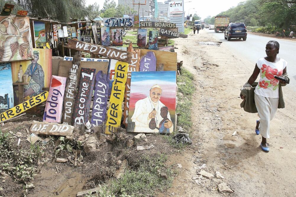 Una mujer camina junto a una pintura del Papa con un niño Maasai, en Nairobi. Francisco llega hoy a la capital keniata (GORAN TOMASEVIC . REUTERS)