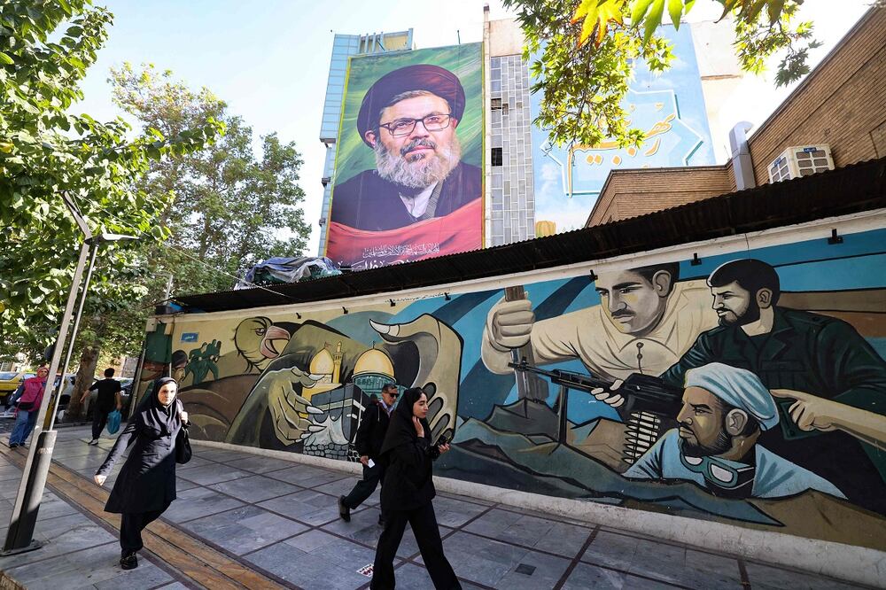 La gente pasa junto a una pintura mural y un cartel del clérigo libanés asesinado Hashem Safieddine en una calle de Teherán el 26 de octubre de 2024. Foto: AFP