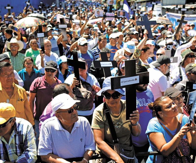 Con mensajes en cruces negras, manifestantes reprocharon a la Asamblea salvadoreña la negativa a dar el préstamo al Ejecutivo, en San Salvador. JOSÉ CABEZAS. EFE