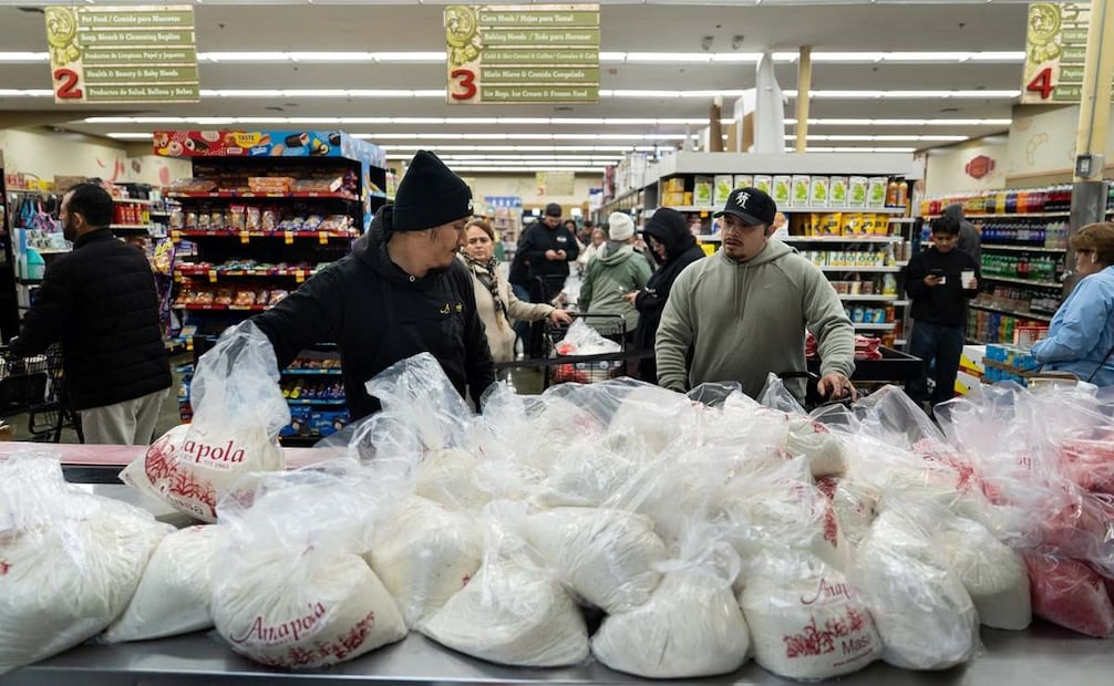 Alex Díaz, a la izquierda, toma una bolsa de masa para hacer tamales, mientras otros compradores esperan en fila en el mercado Amapola en Downey, California. Foto: Jae C. Hong. AP