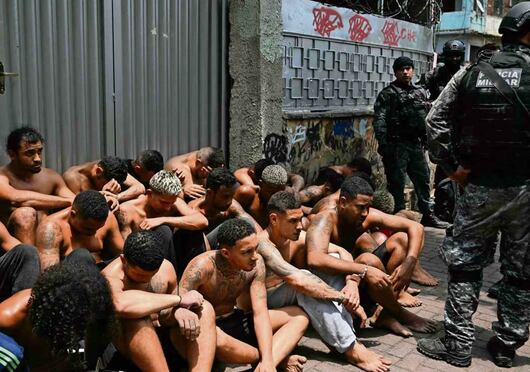 Agentes custodian a presuntos delincuentes arrestados durante el operativo en la favela Vila Cruzeiro. Foto: Mauro Pimentel / AFP