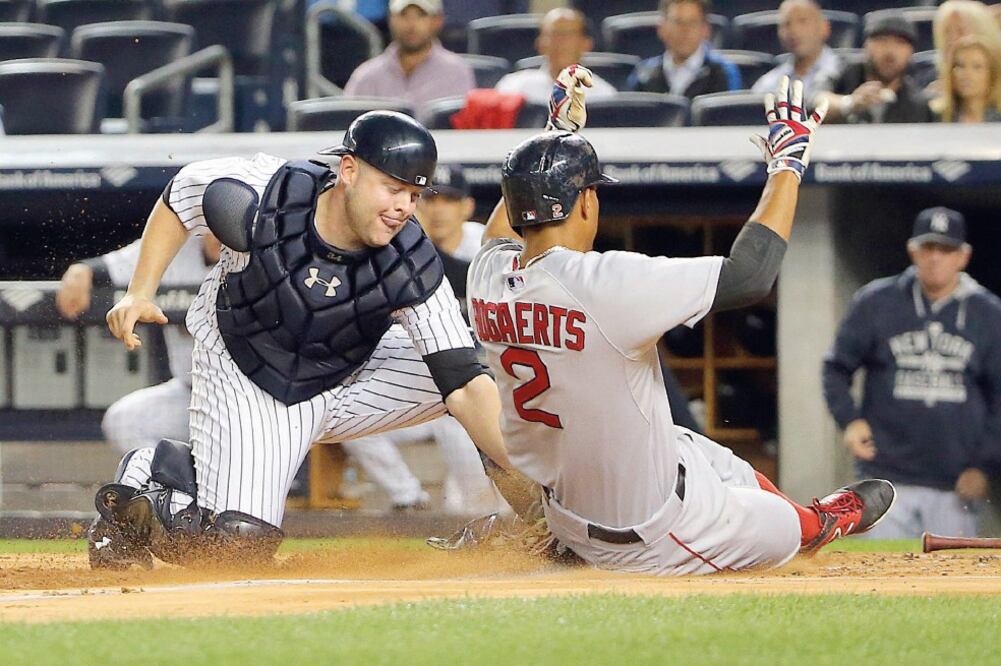 Xander Bogaerts (2) se barre y llega quieto a home, ante el intento desesperado del catcher Brian McCann por frenarlo, en el primer episodio (ANTHONY GRUPPUSO. USA TODAY SPORTS)