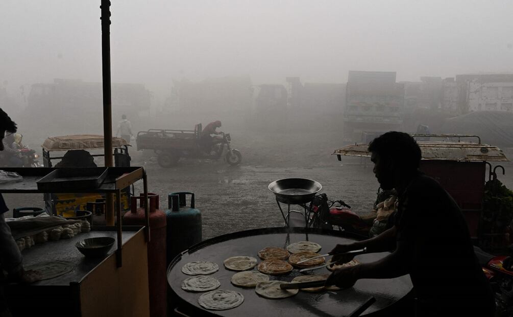 Un trabajador hace pan en una carretera en medio de una intensa contaminación en Lahore. Foto: AFP