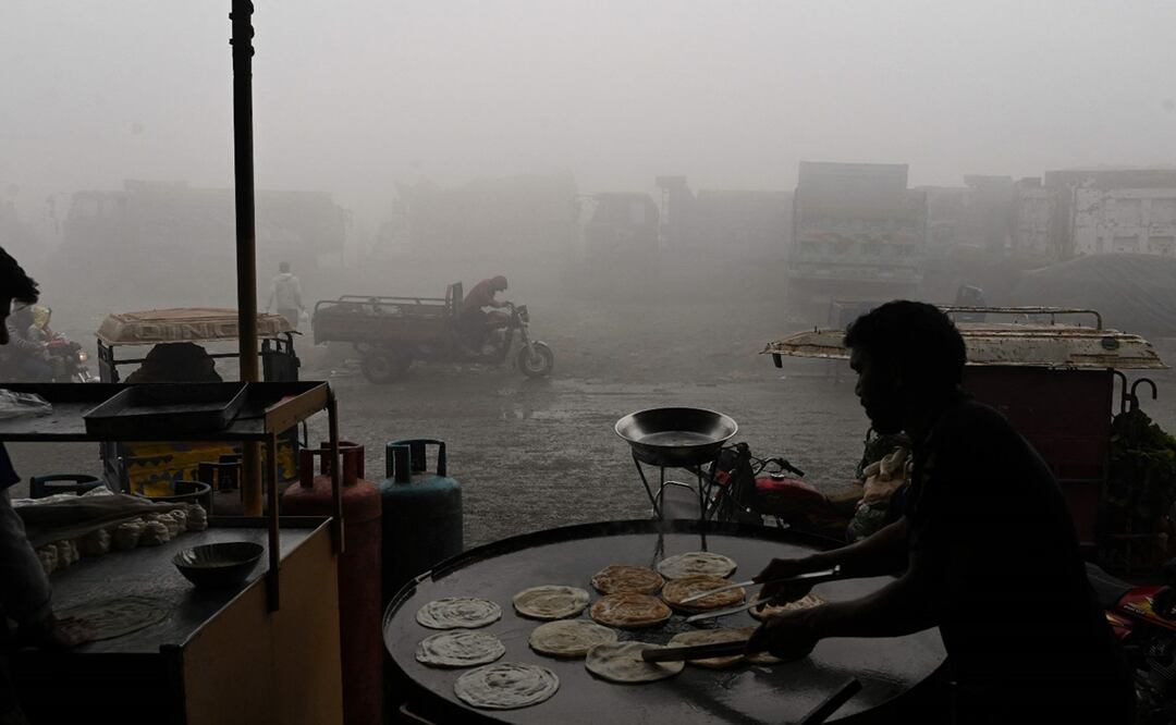 Un trabajador hace pan en una carretera en medio de una intensa contaminación en Lahore. Foto: AFP