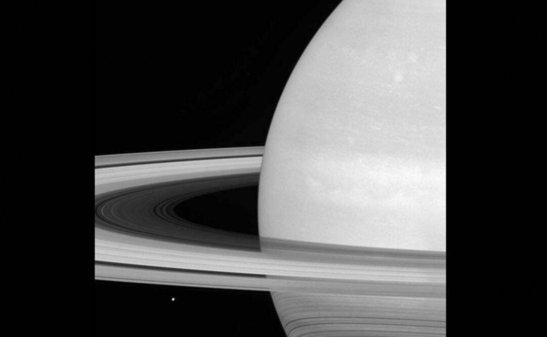 En esta imagen difundida por la NASA se ve una de las lunas de Saturno, Mimas, apenas visible por los anillos del planeta