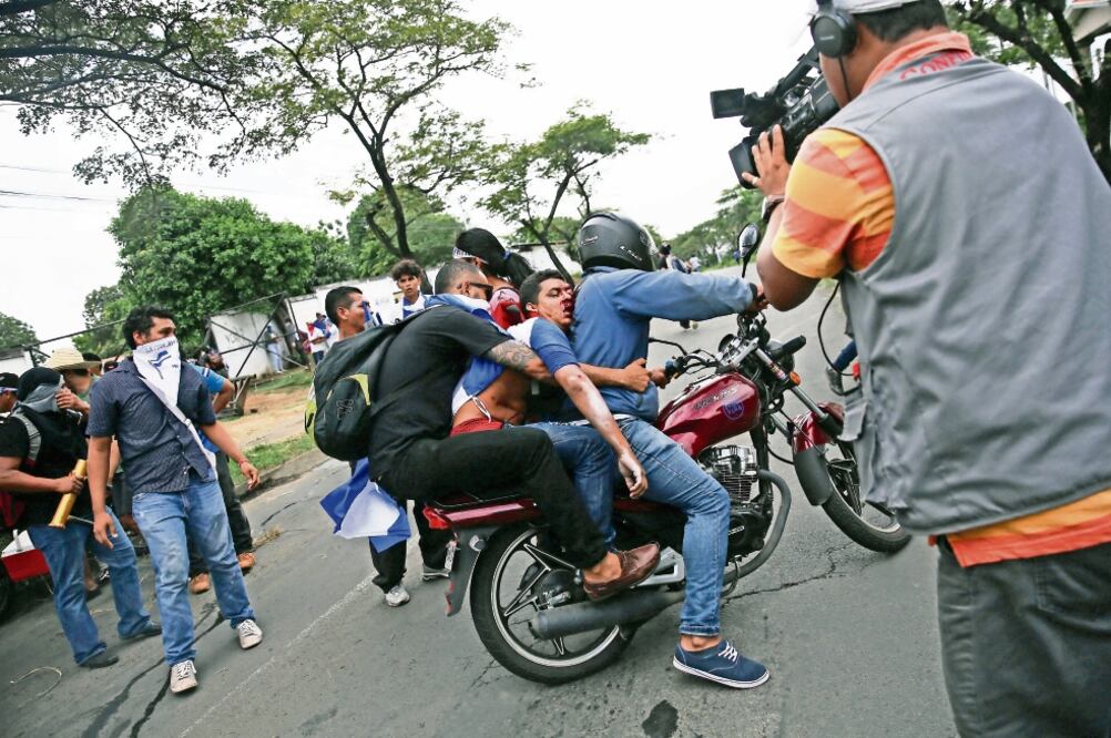 Un hombre en motocicleta transporta a un herido durante los ataques a manifestaciones después de la Marcha de las Flores. Foto: BIENVENIDO VELASCO. EFE