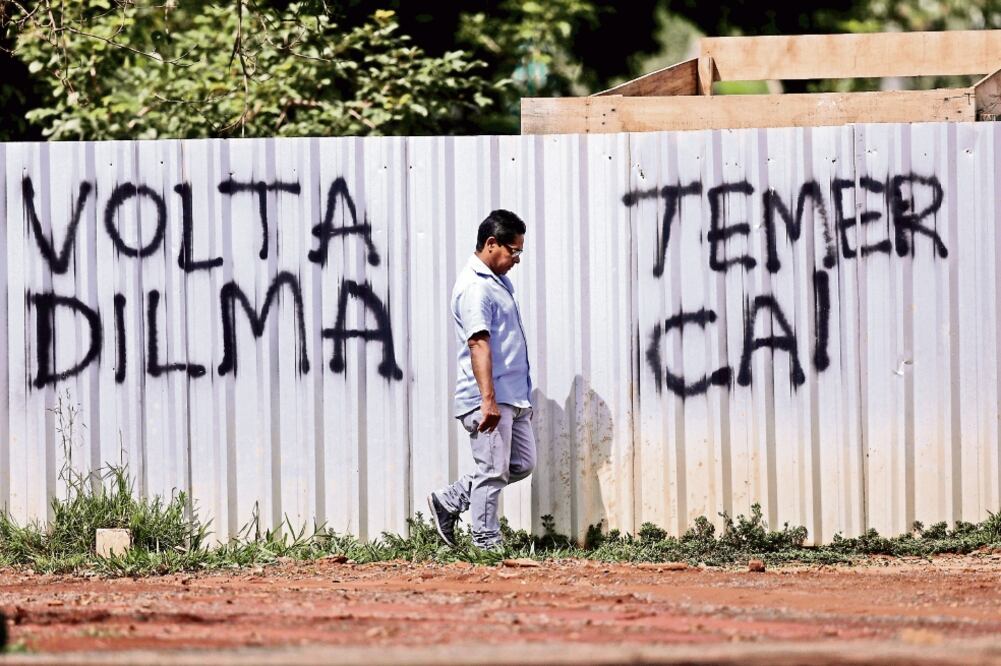 Un hombre camina frente a un grafiti en el que se pide el regreso de la ex presidenta Dilma Rouseff y la caída de Michel Temer (UESLEI MARCELINO. REUTERS)